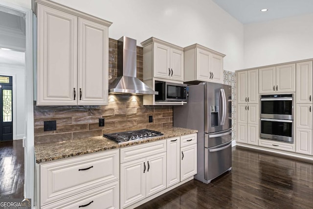 kitchen featuring appliances with stainless steel finishes, wall chimney exhaust hood, dark wood-type flooring, stone counters, and recessed lighting