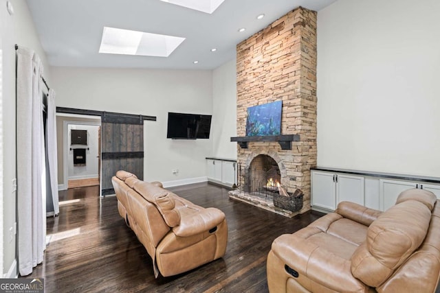 living room with a skylight, a stone fireplace, wood finished floors, baseboards, and recessed lighting