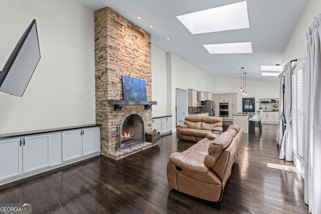 living area with a skylight, a fireplace, dark wood-type flooring, and high vaulted ceiling