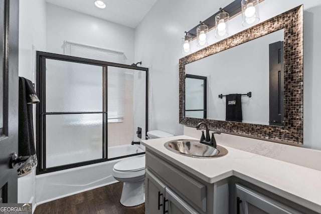 bathroom with toilet, wood finished floors, vanity, enclosed tub / shower combo, and recessed lighting
