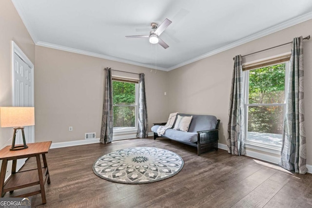 sitting room with a ceiling fan, wood finished floors, baseboards, and ornamental molding