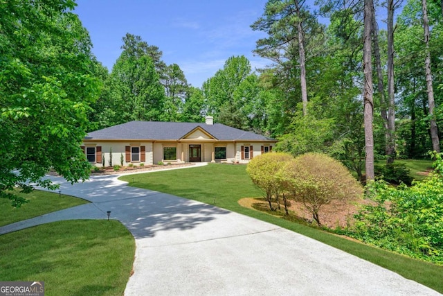 single story home with curved driveway, a front lawn, and a chimney