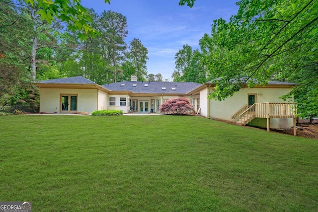 back of property with french doors, a yard, and a chimney