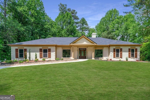 view of front of property with a front lawn, a chimney, a shingled roof, and stucco siding