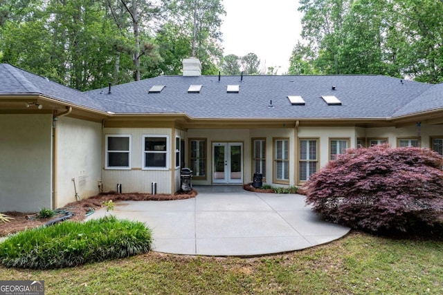rear view of house featuring french doors, a patio, roof with shingles, a chimney, and stucco siding