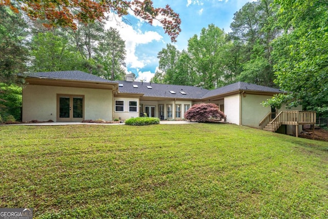 rear view of property featuring french doors, stucco siding, a chimney, a yard, and stairway