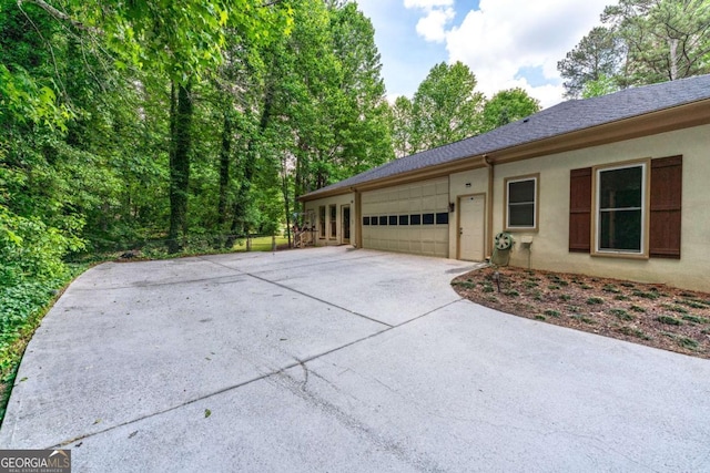 view of property exterior featuring concrete driveway, an attached garage, and stucco siding