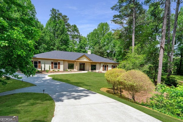 single story home with driveway, a front lawn, and a chimney
