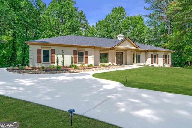 view of front of house featuring a chimney, a front lawn, stucco siding, and a shingled roof