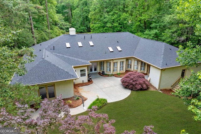 back of property with roof with shingles, a patio area, stucco siding, french doors, and a yard