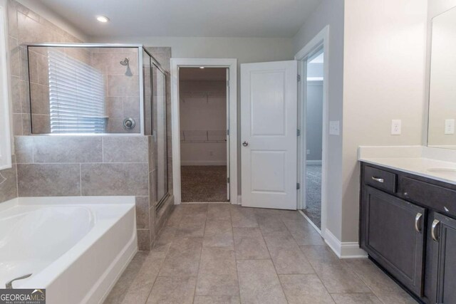 4183 May Apple Ln, Atlanta, GA 30349 - bathroom featuring a stall shower, a garden tub, a walk in closet, vanity, and baseboards