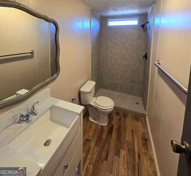 916 Friendly Mission Ln, Cornelia, GA 30531 - bathroom featuring a textured ceiling, wood finished floors, tiled shower, toilet, and vanity