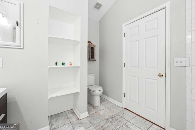 bathroom featuring vanity, toilet, marble look tile flooring, and baseboards