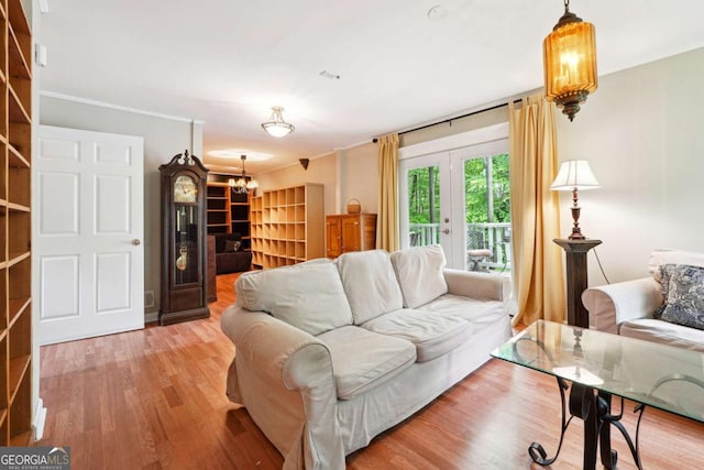 living room featuring wood finished floors, a chandelier, and crown molding