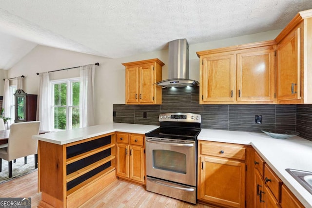 kitchen with wall chimney exhaust hood, stainless steel electric stove, light wood-type flooring, a peninsula, and light countertops