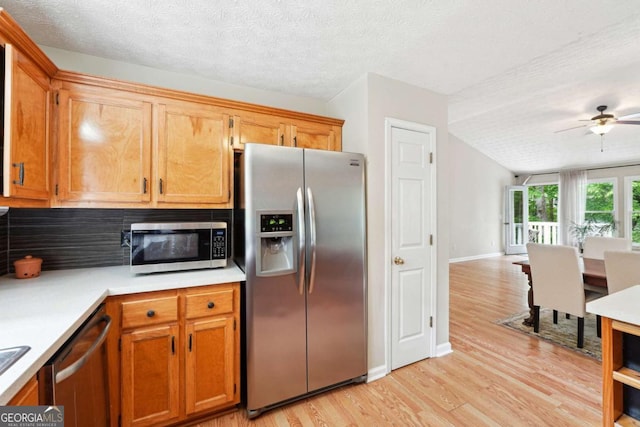 kitchen with stainless steel appliances, light wood finished floors, light countertops, a textured ceiling, and a ceiling fan