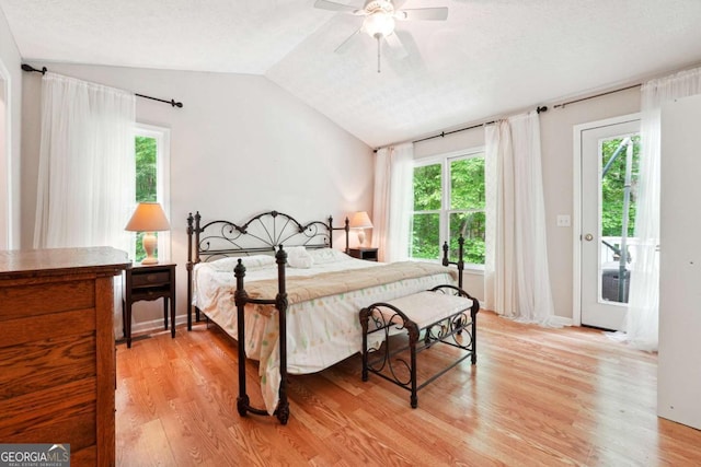 bedroom featuring light wood finished floors, multiple windows, vaulted ceiling, ceiling fan, and a textured ceiling