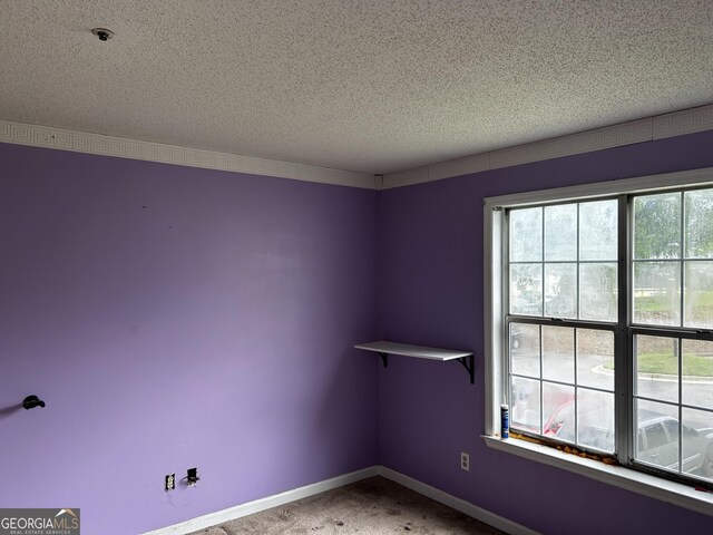 spare room with a textured ceiling, fire sprinkler in ceiling, carpet flooring, and baseboards