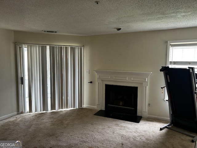 unfurnished living room with carpet, a fireplace with flush hearth, a textured ceiling, and baseboards