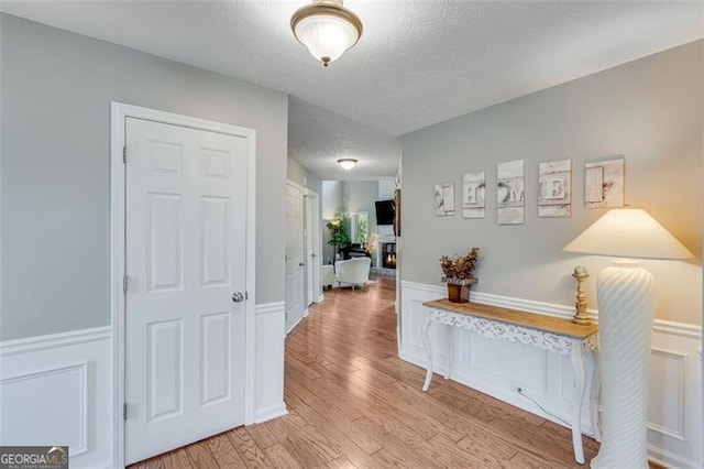 3517 Ridgemill Cir, Dacula, GA 30019 - hall with light wood finished floors, a textured ceiling, and a wainscoted wall