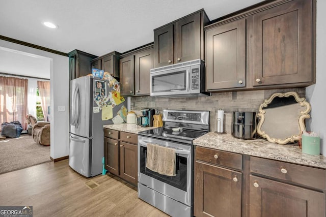 315 April Trce, Dawsonville, GA 30534 - kitchen featuring appliances with stainless steel finishes, light wood-style flooring, tasteful backsplash, dark brown cabinetry, and light stone counters