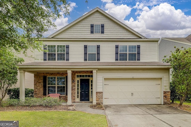 traditional-style house with stone siding, a garage, covered porch, driveway, and a front yard
