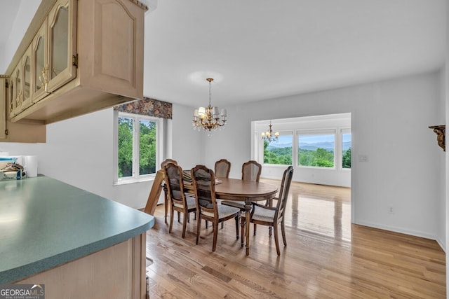 dining area with a chandelier, light wood finished floors, and baseboards