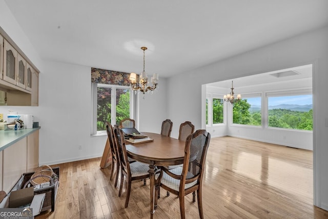 dining room featuring a chandelier, light wood-style floors, and baseboards