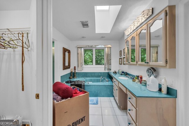 full bathroom with a skylight, vanity, a bath, and tile patterned flooring