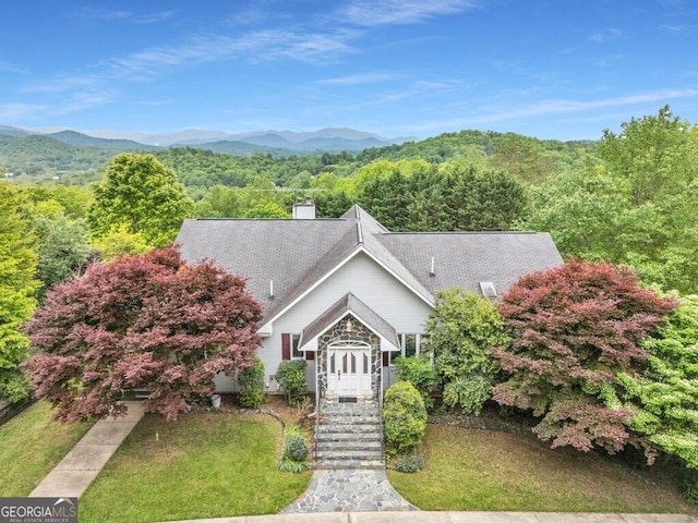 view of front of property featuring a mountain view, a wooded view, and a chimney