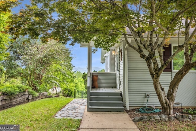 view of exterior entry with a yard and a wooden deck