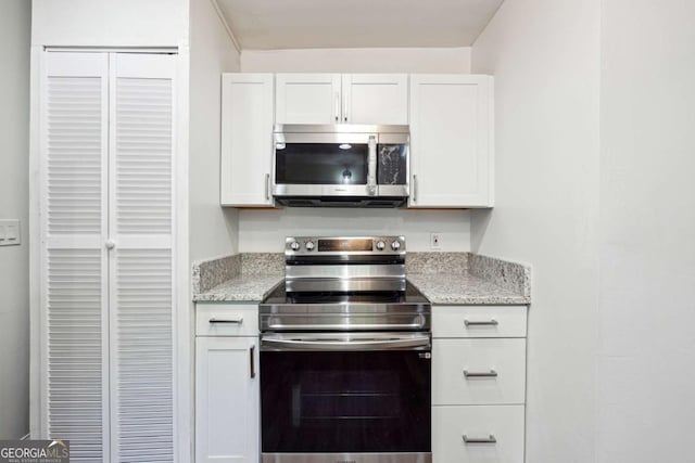 kitchen featuring stainless steel appliances, white cabinetry, and light stone countertops