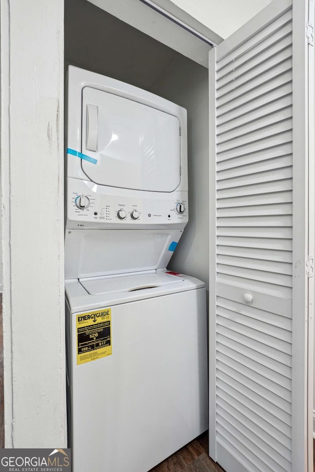 laundry room featuring estacked washer and dryer and dark wood-style flooring