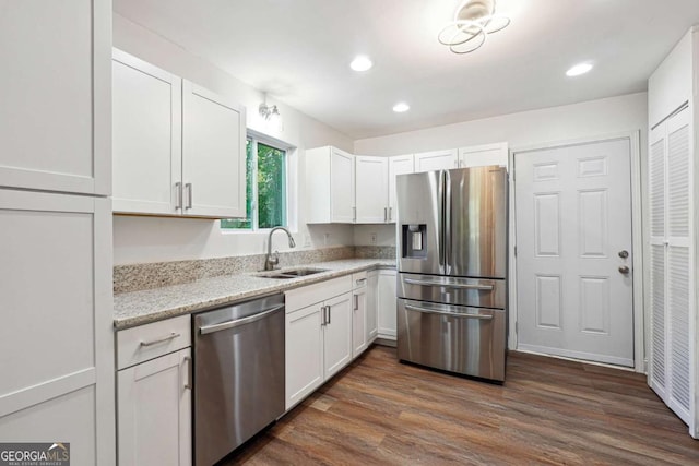 kitchen with appliances with stainless steel finishes, a sink, white cabinetry, recessed lighting, and light stone counters