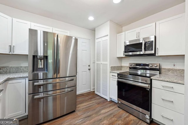 kitchen featuring appliances with stainless steel finishes, white cabinets, dark wood-style floors, recessed lighting, and light stone counters