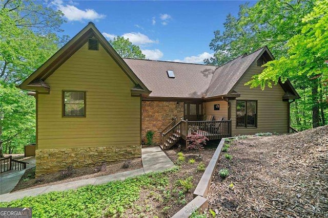 rear view of house with a deck and stone siding