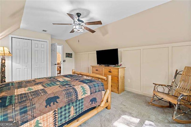 carpeted bedroom with a decorative wall, vaulted ceiling, and a ceiling fan