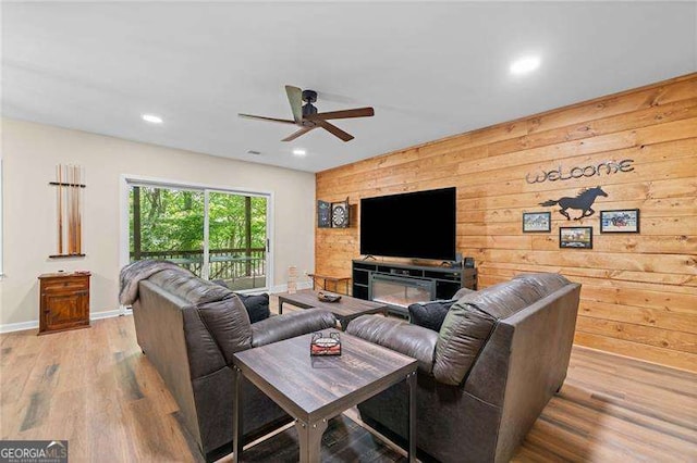 living room with wooden walls, ceiling fan, baseboards, wood finished floors, and recessed lighting