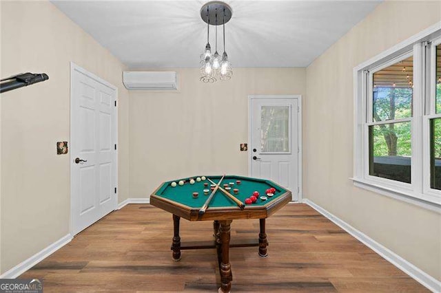 playroom featuring an AC wall unit, baseboards, and wood finished floors