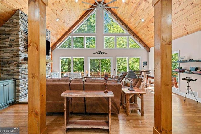 living area featuring high vaulted ceiling, wood ceiling, wood finished floors, and plenty of natural light