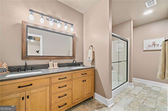 bathroom featuring baseboards, a shower stall, and double vanity