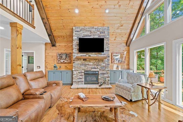 living room with high vaulted ceiling, a fireplace, wooden ceiling, light wood-style floors, and wooden walls