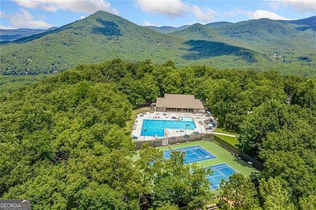 bird's eye view of a pool, mountains, and a heavily wooded area
