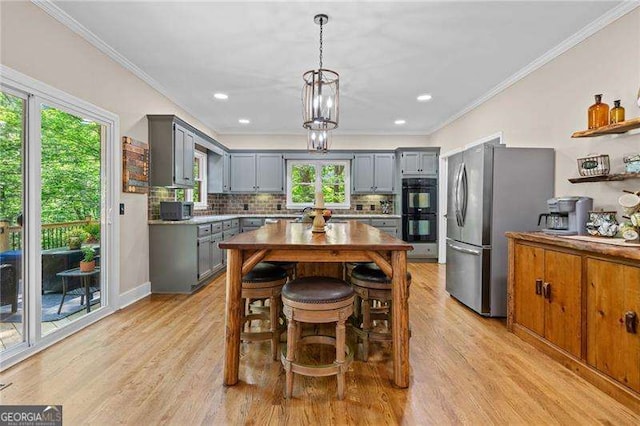 kitchen with gray cabinetry, freestanding refrigerator, plenty of natural light, tasteful backsplash, and crown molding