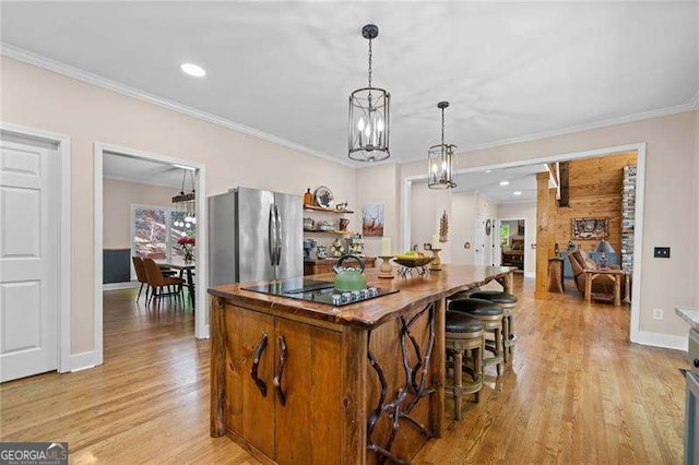 kitchen with black electric stovetop, a chandelier, a center island, light wood-type flooring, and ornamental molding