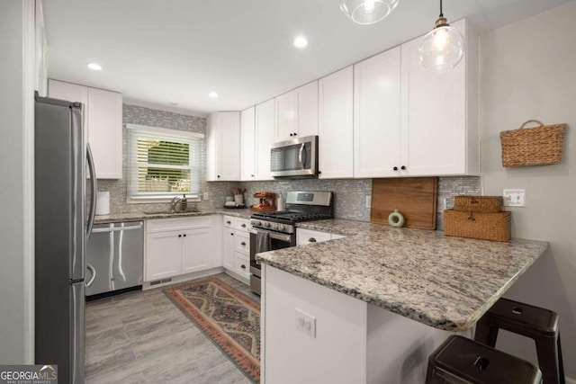 283 Norton Cir SE, Smyrna, GA 30082 - kitchen featuring stainless steel appliances, a sink, a peninsula, light stone counters, and white cabinetry