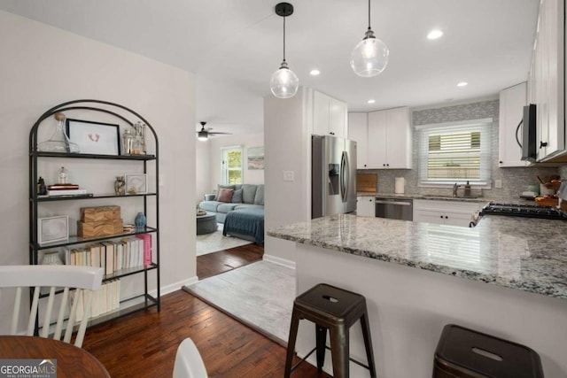 283 Norton Cir SE, Smyrna, GA 30082 - kitchen with appliances with stainless steel finishes, dark wood-type flooring, a peninsula, white cabinets, and healthy amount of natural light