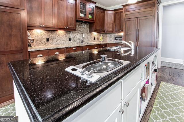 1365 Ivy Plantation, Monroe, GA 30656 - kitchen featuring wood finished floors, backsplash, glass insert cabinets, dark stone countertops, and crown molding