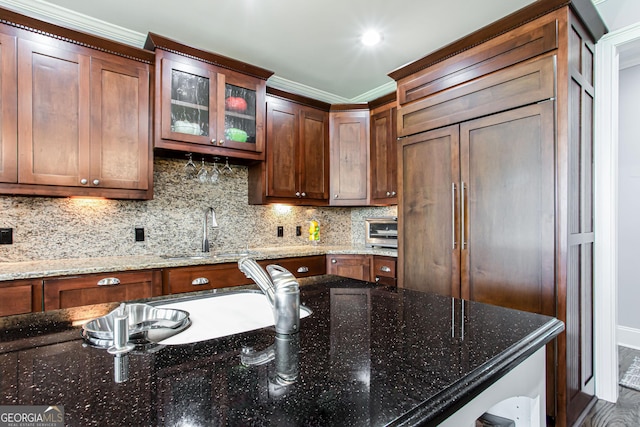 1365 Ivy Plantation, Monroe, GA 30656 - kitchen featuring ornamental molding, paneled fridge, backsplash, glass insert cabinets, and dark stone countertops
