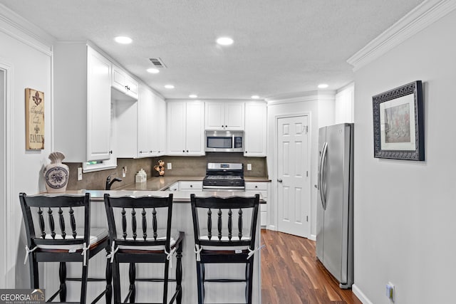 226 Le Paradis Blvd, Sharpsburg, GA 30277 - kitchen with appliances with stainless steel finishes, a peninsula, ornamental molding, white cabinets, and a kitchen bar